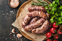 Raw Sausages Or Bratwurst And Ingredients For Cooking On Dark Stone Background. Top View With Copy Space.