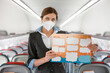 © Kostiantyn - Female flight attendant in face mask holding instruction booklet