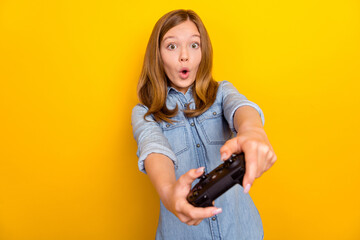 Photo of impressed small brown hairdo girl playstation look camera wear denim shirt isolated on bright yellow color background