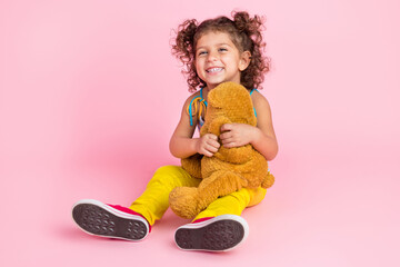 Portrait of attractive cheerful wavy-haired girl playing with bear resting having fun isolated over pink pastel color background