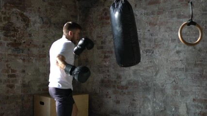 Wall Mural - Confident sportsman with muscular body punching boxing bag during training. Young strong man working out for keep fit and healthy. Cross fit training. Motivation, discipline and strength