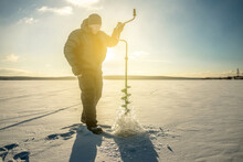 Fisherman Is Fishing In A Hole On A Large Frozen Lake On A Sunny Day. The Joy Of Winter Fishing
