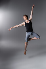 Wall Mural - young and graceful ballet dancer gesturing while levitating on dark grey