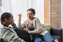 Smiling African American Woman Talking With Teenage Daughter On Couch At Home