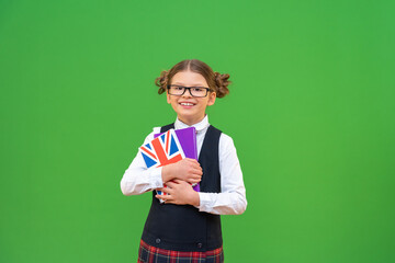 Wall Mural - Learning English. foreign language courses. a schoolgirl with pigtails on a green isolated background. the book of the English language.