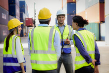 The Caucasian Manager Or Leader Team Is Assignmenting And Training A Job For Team Of Supervisor, Foreman And Labor In The Morning Meeting Before Work In A Warehouse Full Of Containers.