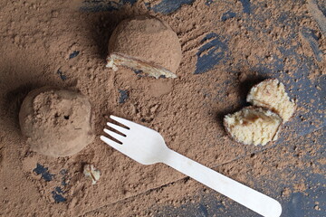 Wall Mural - round chocolate coffee cake on a black slate board on cocoa with a wooden fork. Dessert Chocolate Day