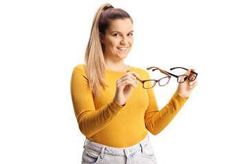 Young female holding two pairs of eyeglasses and smiling at camera