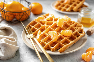 Wall Mural - Homemade ginger waffles with tangerines. Delicious Christmas pastries on a light background closeup	