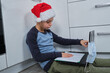 chłopak w czapce świętego mikołaja, uczestniczy w lekcjach online 