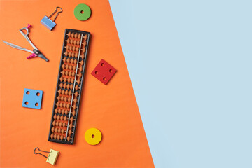 Creative lay out of mental mathematics items. Mental arithmetic for kids. School items for kids. Abacus with school supplies, drawing compass on colored background. Mental mathematics, math concept