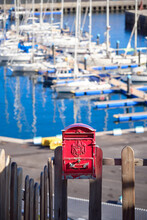 Vertical Shot Of A Red Vintage Mailbox In Front Of Sailing Yachts