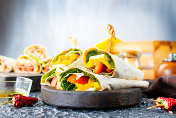 Wall Mural - Healthy tortilla wraps viewed from side on wooden cutting board, tortilla with chicken and vegetables