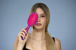 © Alena - bright young blonde woman holding a comb in her hands. Blue background