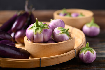 Wall Mural - Fresh organic Thai purple eggplant in small basket on wooden background, Food ingredient