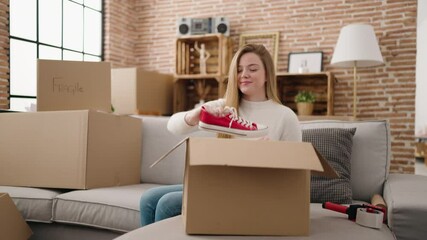 Canvas Print - Young blonde woman smiling confident unboxing sneakers on package at new home