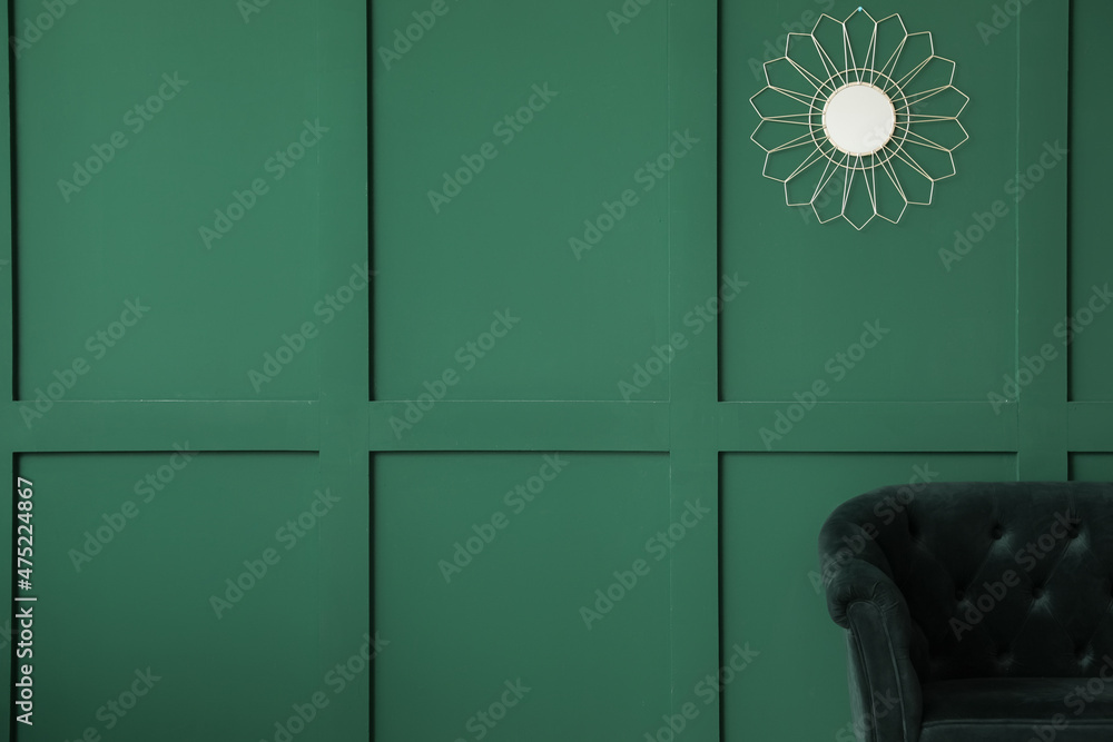 Modern interior with stylish couch and mirror on green wall background