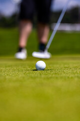 Wall Mural - Vertical shot of a white golf ball and a person on blurred background