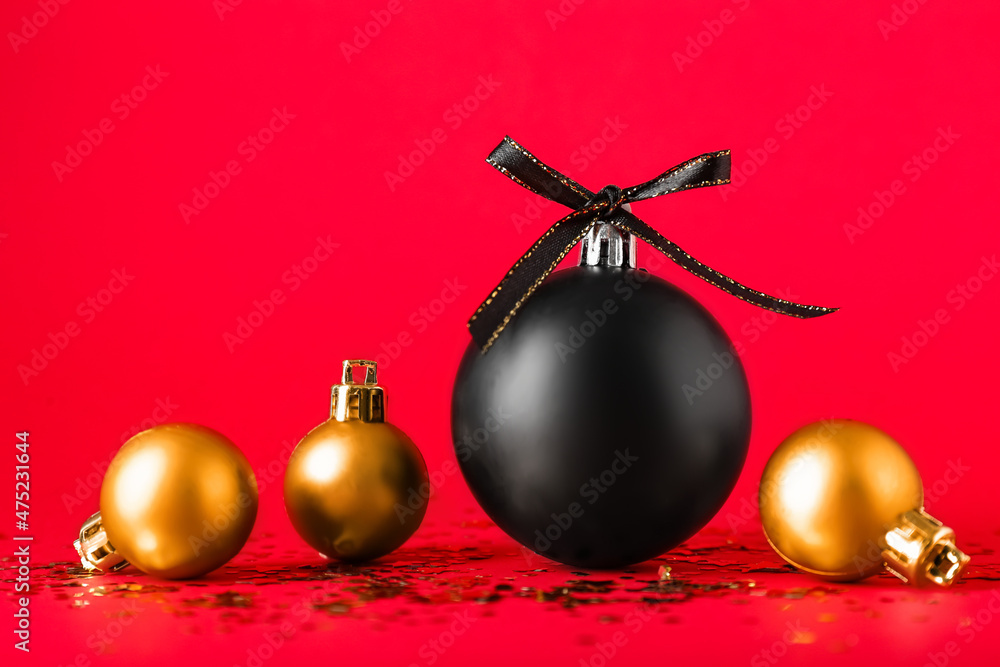 Black and golden Christmas balls on red background
