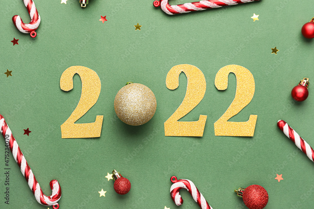 Figure 2022 and Christmas decorations on green background
