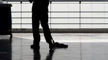 Silhouette Image Of Cleaning Service People Sweeping The Floor With A Mop And Other Equipment On The Trolley.