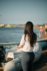 Wall Mural - Sporty woman on the seashore wearing white shirt and leggings. Clothed fitness woman on the beach.