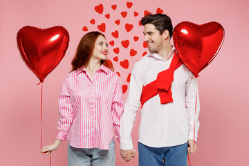 Wall Mural - Young couple two friends woman man wear shirt hold red bunch of inflatable balloons look to each other isolated on plain pink background studio portrait Valentine's Day birthday holiday party concept