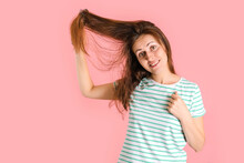 Happy Brunette Fooling Around Combing Her Hair On A Pink Background