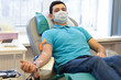 bone marrow donation. man in medical mask, male hand holding red ball, blood transfusion system, blood bag. soft focus