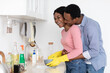 © Prostock-studio - Black guy hugging his laughing girlfriend washing dishes at kitchen