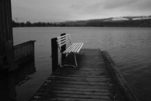 Grayscale Of A Lonely Bench On A Pier At The Sea