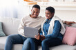 © Prostock-studio - African american couple sitting on couch, using laptop