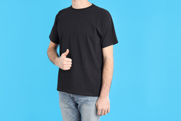 Man in blank black t-shirt on blue background