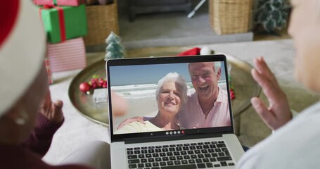 Wall Mural - Diverse senior female friends using laptop for christmas video call with happy couple on screen