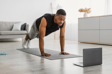 Wall Mural - Sporty Black Guy Exercising At Laptop Doing Plank At Home