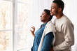 © Prostock-studio - Black couple standing near glass window and looking