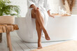 canvas print picture - African Female Touching Legs Sitting On Bathtub In Bathroom, Cropped