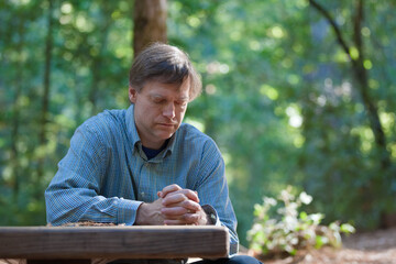 Man praying alone in middle of forest