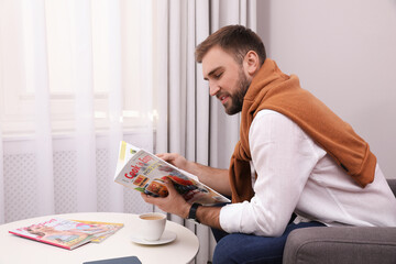 Canvas Print - Handsome man reading magazine near window at home