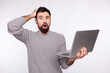 © Tetiana - Photo of young guy amazed shock use laptop news information deadline isolated over grey color background
