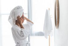 Joyful African American Woman Adjusting Towel And Looking At Mirror In Bathroom