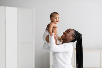 Black woman playing with her cute little baby at home