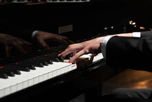 Closeup Photo Of Male Person Hands In A Black Jacket And White Shirt Playing Black And White Piano Keys. Musical Instrument And Music