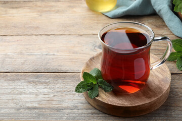 Cup of hot aromatic tea with mint on wooden table. Space for text