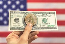 Hand With Bitcoin With Dollar On USA Flag Background. Cryptocurrency And United States Of America Concept