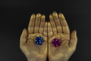 Poster - Golden hands with miniature gift bows isolated on black background