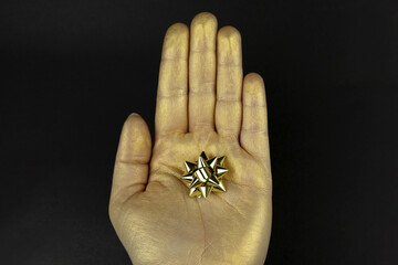 Sticker - Golden hand with a miniature gift bow isolated on black background