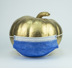 Poster - Golden pumpkin wearing face mask isolated on blue background with space for text