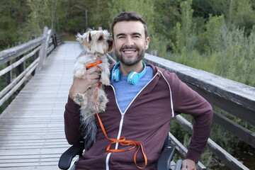 Handsome man on a wheelchair with his cute Yorkshire terrier