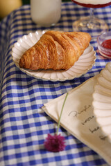 Poster - Closeup shot of a fresh croissant served on the white plate with a double color sweet dessert